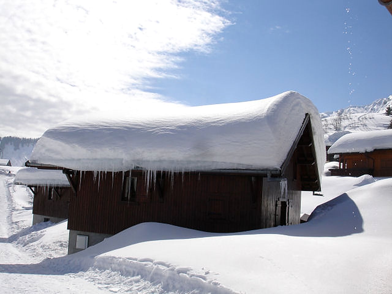 Le toit enneigé d'un chalet Panda sous un ciel bleu, vu depuis la piste piéton